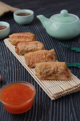Dimsum, as the name Keicak, is filled with carrots, chicken, mushrooms and wrapped in tofu skin, side angle with black background