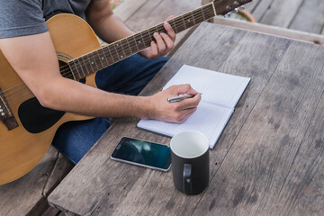 songwriter thinking and writing notes,lyrics in book at studio.man playing live acoustic...