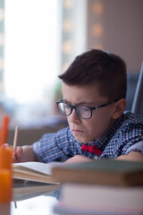 A very cute boy is studying and writing his homework