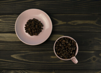 fragrant rich coffee beans of different varieties on a dark wooden surface in a pink coffee cup and saucer. for banners, flyers, splash screens, menu labels