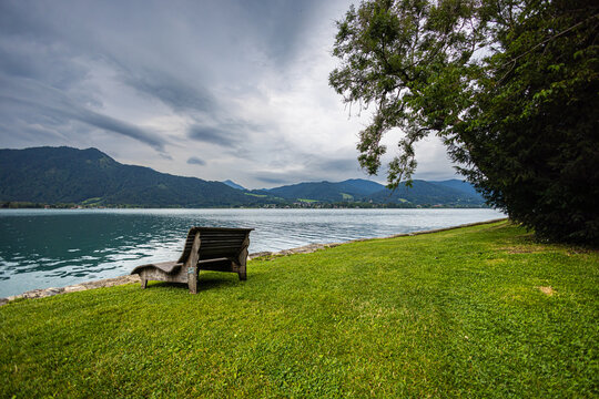At Tegernsee on a slightly rainy summer day. Gray rain clouds move in the sky over the lake, covering the  Alps panorama. Clear water of the mountain lake. Tegernsee is a town in Bavaria, Germany