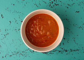Top view of a bowl of Indian cottage cheese and tomato sauce in a white bowl.