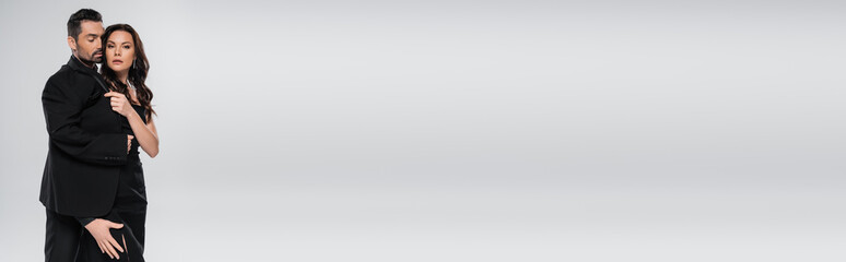 passionate man touching leg of brunette woman in dress on grey background, banner.