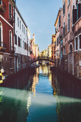 Fototapeta na wymiar Canal in sunshine with bridge in Venice, Italy.