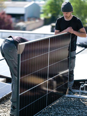 Male team engineers installing stand-alone solar photovoltaic panel system. Electricians mounting blue solar module on roof of company roof. Alternative energy concept