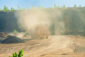 Large quarry dump truck to remove the rock mass from the quarry for the extraction of minerals. Truck on the road at the waste rock dump during ore mining