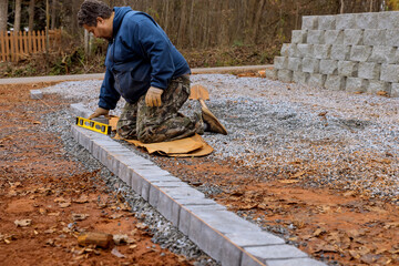 Construction worker is installing arranging precast concrete pavers stones for road sidewalk at construction site