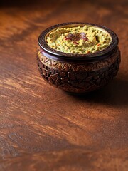 Hummus dip with chickpea and parsley in a traditional ceramic bowl on wood surface with toasted bread slices and olive oil on wooden board. Added spices.