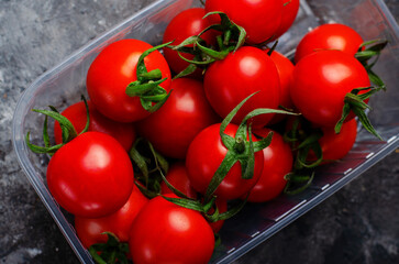 Cherry tomatoes in a plastic container on Dark Background