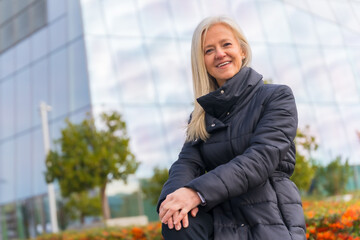 Corporate portrait of middle-aged businesswoman, exterior of office skyscraper looking