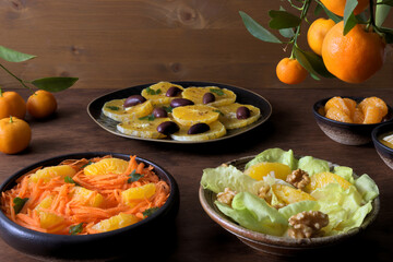 Orange salads with different ingredients. Three fruit salads on a table.