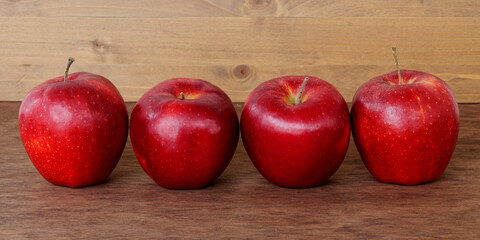 Red apple fruits. Four raw ripe perfect apples on wooden table.