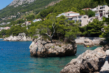Fototapeta na wymiar Idyllic islet on Punta Rata beach in Brela, Makarska riviera of Dalmatia, Croatia symbol tree stone of Brela