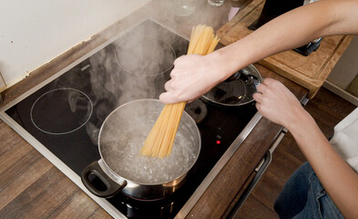 Young woman cooks spaghetti in the kitchen - home shooting