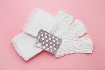 Different types of female pads and contraceptive tablets during the menstrual cycle on a pink background