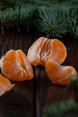 A peeled tangerine on a wooden table among spruce twigs