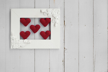 Red crochet hearts on a frame. Love´s concept wooden white background.