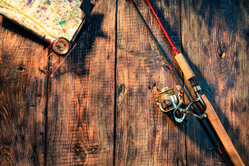 Fishing spinning with a reel on a wooden background. Spinning and map with compass. Fishing...