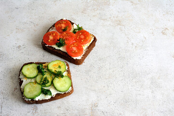healthy toasts with curd cheese, slices of tomato and cucumber, parsley and spices, close-up