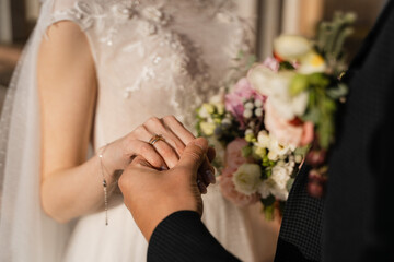 Obraz na płótnie Canvas the groom holds the bride's hand close-up