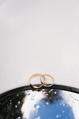 wedding rings made of gold on a light background with water drops from the rain