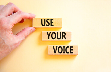 Use your voice symbol. Concept words Use your voice on wooden blocks on a beautiful white table white background. Businessman hand. Business and use your voice concept. Copy space.