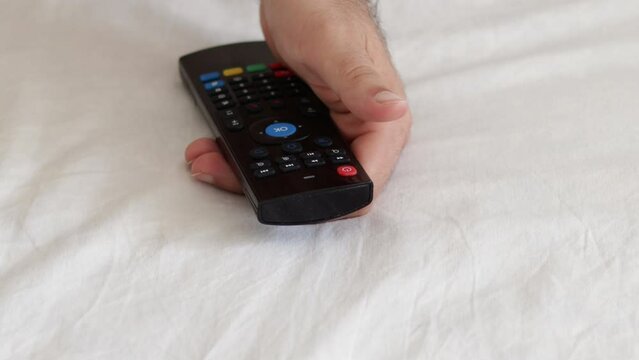 cute baby boy playing with remote tv control sitting on bed naket toddler infant with diaper.father man hand turning off television with one hand isolated on blanket close up 4k