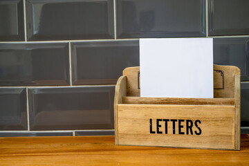 mail letter rack with blank paper on a wooden desk top and tiled walls