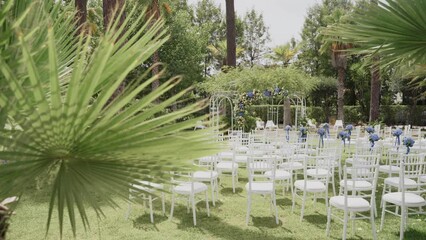 Wedding ceremony chairs and arch in the foreground of palm