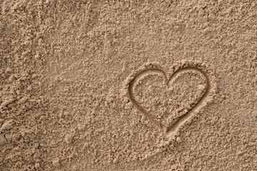 Fototapeta na wymiar Valentine's heart drawn with a stick on the sand 