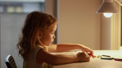 a girl paints a picture in a table light in her room, evening classes at home