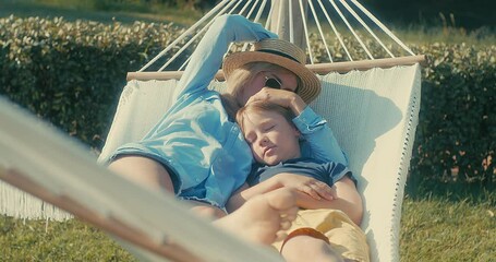 Family fun outdoors, mother and son is resting and using smartphone in hammock in garden, in sunny summer day. Health care, authenticity, sense of balance and calmness. Spend free time. Fresh air.	