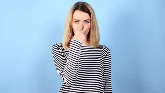 Portrait of young blond woman looking at camera and making I am watching you gesture spying by someone on isolated blue background