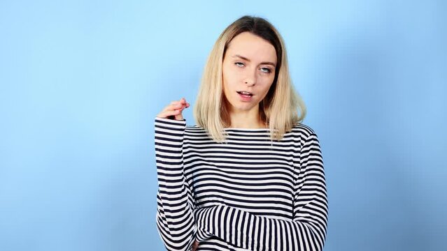 Bored young blond woman rolling up eyes and frowning face expressing tiredness and boredom showing bla bla gesture with hands on isolated blue background