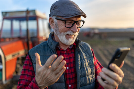 Senior farmer with mobile phone in field