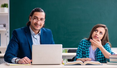 Young handsome teacher and female student in the classroom