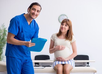 Obraz premium Pregnant woman visiting male doctor gynecologist