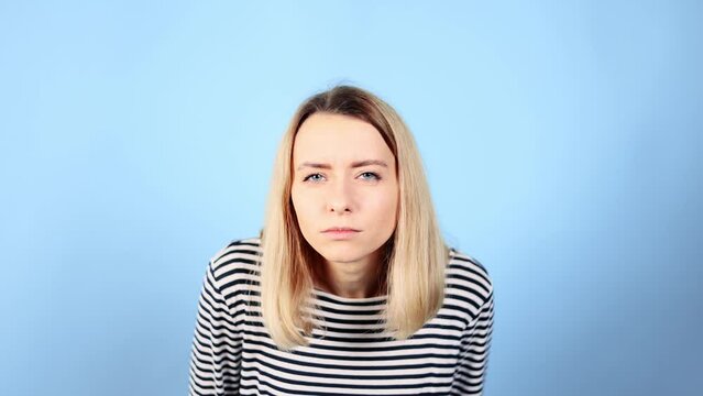 Portrait of puzzled confused young blond woman staring at camera while looking at something and can't understand what it is on isolated blue background 