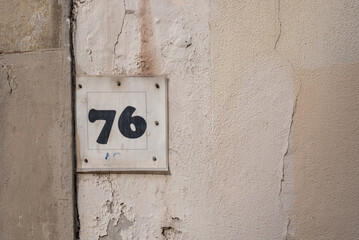 Number 76 on the yellow shabby wall with stains