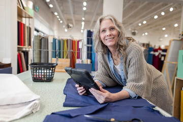 Portrait smiling female businesswoman with digital tablet in fabric st