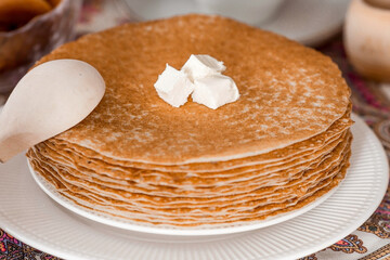 Russian traditions. Russian holiday Maslenitsa. Still life with a cup of tea, a stack of pancakes, sour cream, honey, cubes of butter, bagels, dried fruits, caramel cockerel and samovars.