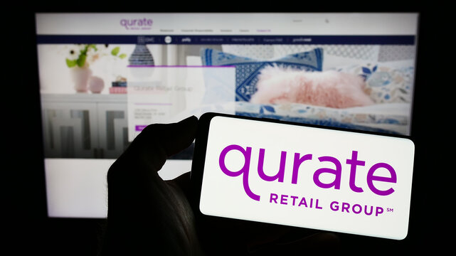 Stuttgart, Germany - 01-01-2023: Person holding mobile phone with logo of American media company Qurate Retail Inc. on screen in front of web page. Focus on phone display.