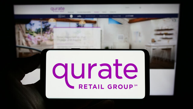 Stuttgart, Germany - 01-01-2023: Person holding cellphone with logo of US media company Qurate Retail Inc. on screen in front of business webpage. Focus on phone display.