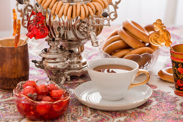 Russian traditions. Tea drinking with a samovar. Still life with a cup of tea, bagels, dried fruits, apple jam, caramel cockerel and Russian samovars.
