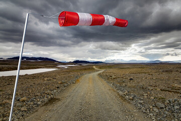Striped Windbag and Mountain Gravel Road with dark clouds, Kaldidalur, Iceland. Concept for creative business ideas. - 558993126