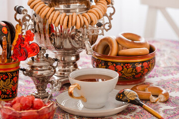 Russian traditions. Tea drinking with a samovar. Still life with a cup of tea, bagels, dried fruits, apple jam, caramel cockerel and Russian samovars.