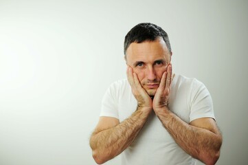 Experiencing doubt adult man put two palms to cheeks He has toothache or he doubts worries about...