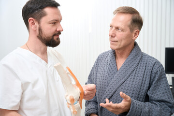 Experienced medical specialist and his patient at orthopedical clinic