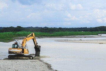 retroexcavadora al borde de un rio recogiendo arena