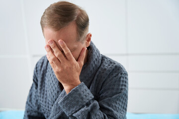 Upset middle-aged patient sits in a bright room